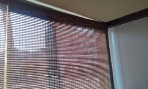 Interior room with brown horizontal blinds covering a window, letting light through