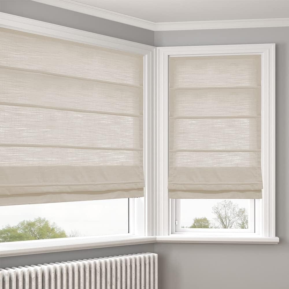 Corner of a room with two white-framed windows wearing beige roman shades, and a radiator below.