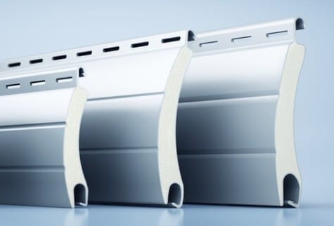 Close-up of three curved aluminum metal profiles with perforated flanges, used in construction.
